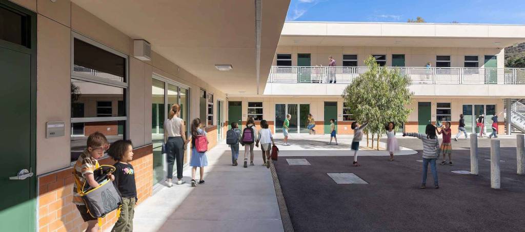 modern school building with large windows, green spaces, and a spacious courtyard.